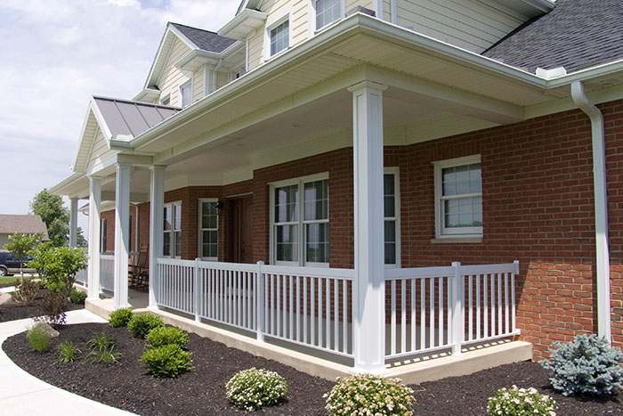 Red brick bungalow with a white wraparound porch and aluminum columns